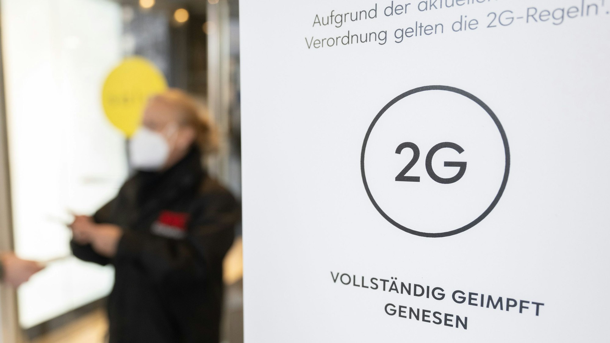 In Niedersachsen und Bayern wurde die 2G-Regel gerichtlich gekippt. Das Symbolfoto aus Stuttgart zeigt eine Mitarbeiterin eines Kaufhauses, die am 12. Januar 2022 am Eingang mit einem Smartphone den Impfnachweis einer Kundin kontrolliert.