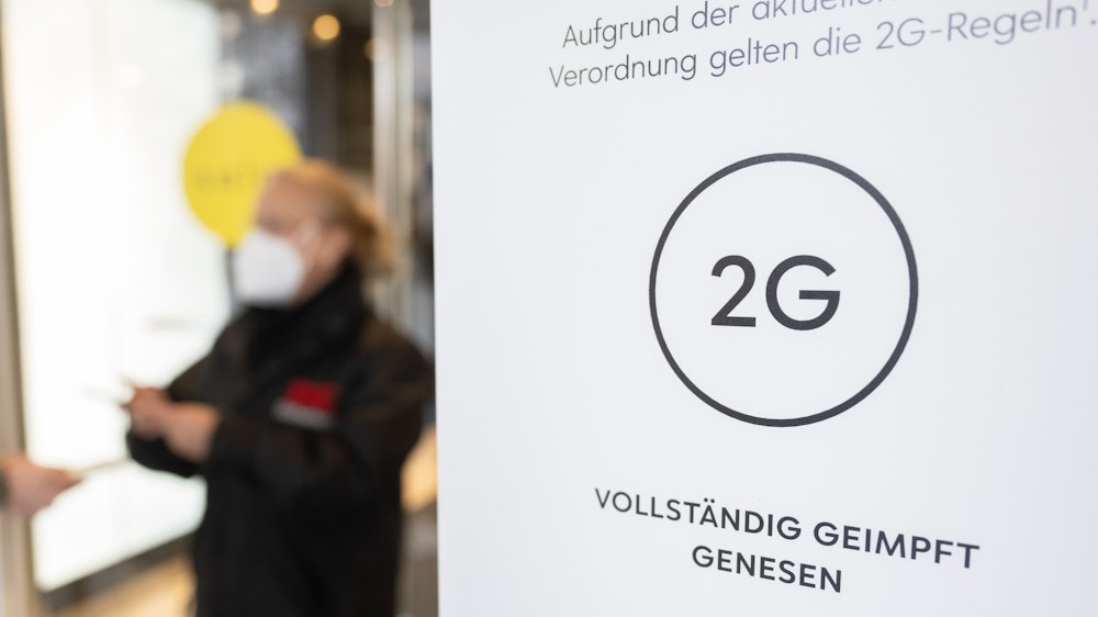 In Niedersachsen und Bayern wurde die 2G-Regel gerichtlich gekippt. Das Symbolfoto aus Stuttgart zeigt eine Mitarbeiterin eines Kaufhauses, die am 12. Januar 2022 am Eingang mit einem Smartphone den Impfnachweis einer Kundin kontrolliert.