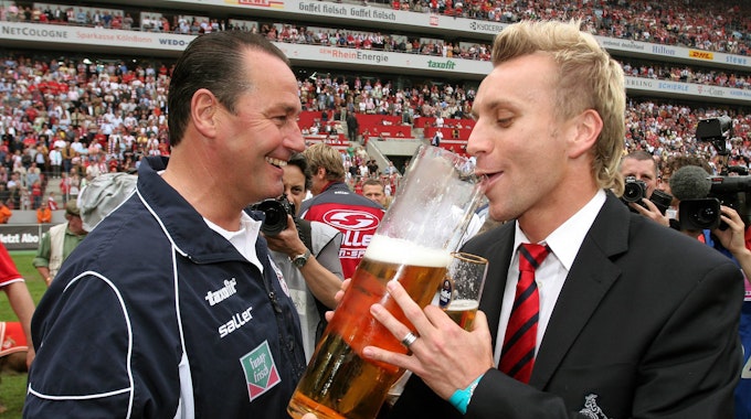 Trainer Huub Stevens (li.) verleitet Sebastian Schindzielorz (beide Köln) während der Aufstiegsfeier zum Bier trinken.