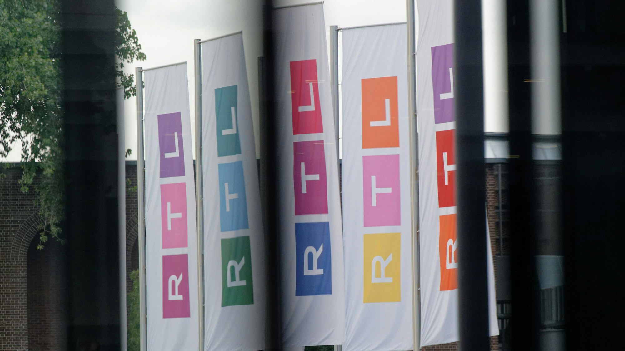 Fahnen des Fernsehsenders RTL stehen auf dem Platz vor dem Firmengebäude.