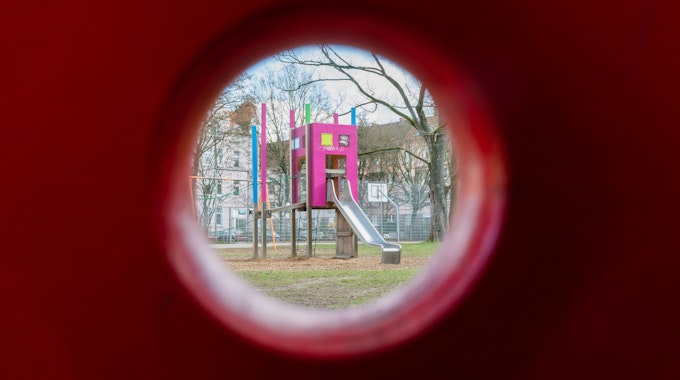 Blick durch ein Schaukelpferd auf eine Rutsche auf einem Kinderspielplatz.