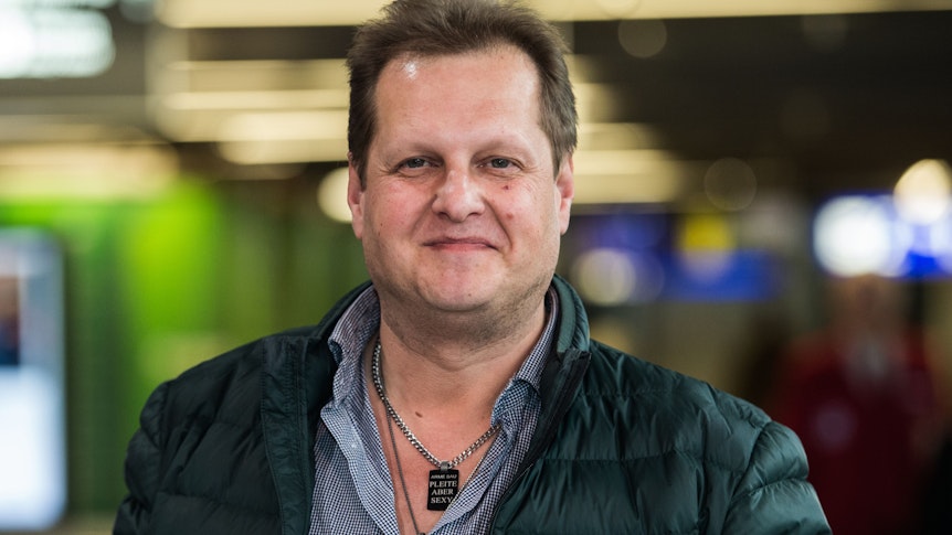 Jens Büchner lächelt 2017 am Flughafen in die Kamera.