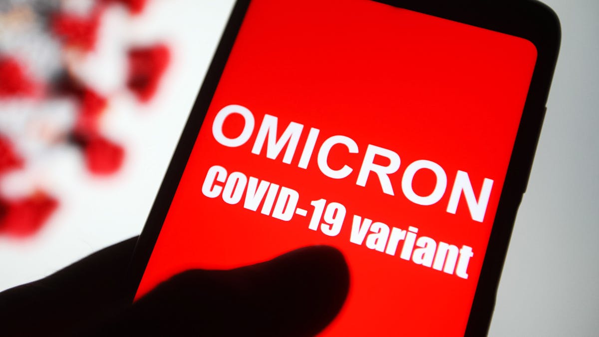 Symbolbild. Auf dem Bildschirm eines Smartphones ist der Text „Omicron COVID-19-variant“ zu lesen.&nbsp;