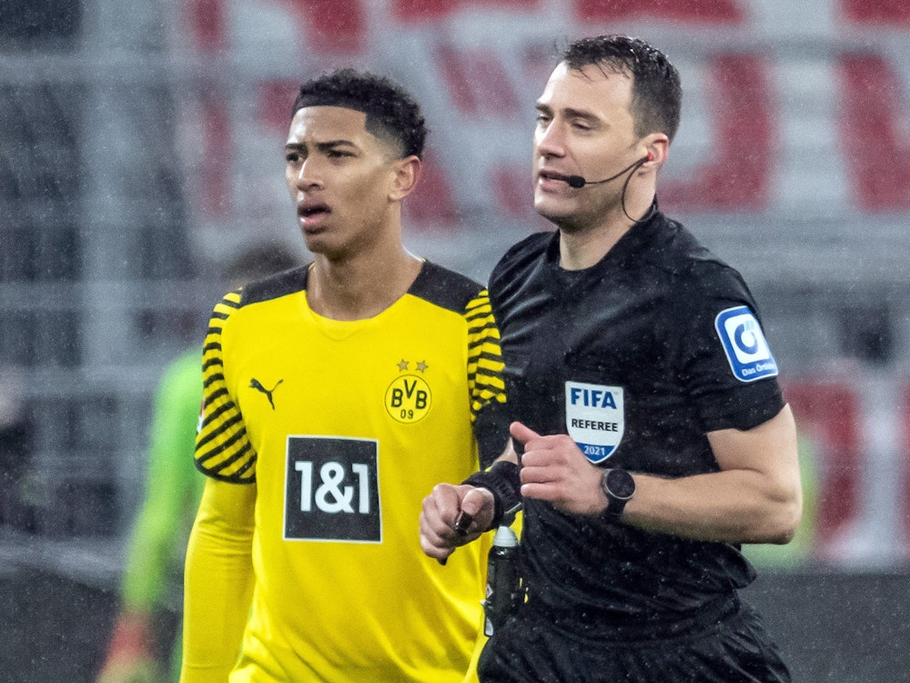 Schiedsrichter Felix Zwayer (r) läuft an Dortmunds Jude Bellingham zum Spielfeldrand, um sich den Videobeweis für den anschließend gegebenen Strafstoß anzuschauen.