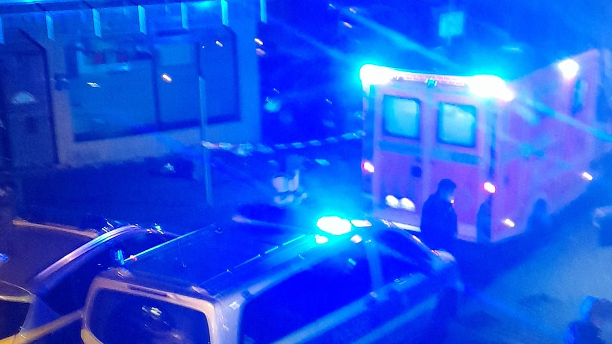 Rettungswagen und Polizeiautos mit Blaulicht stehen in einer Straße
