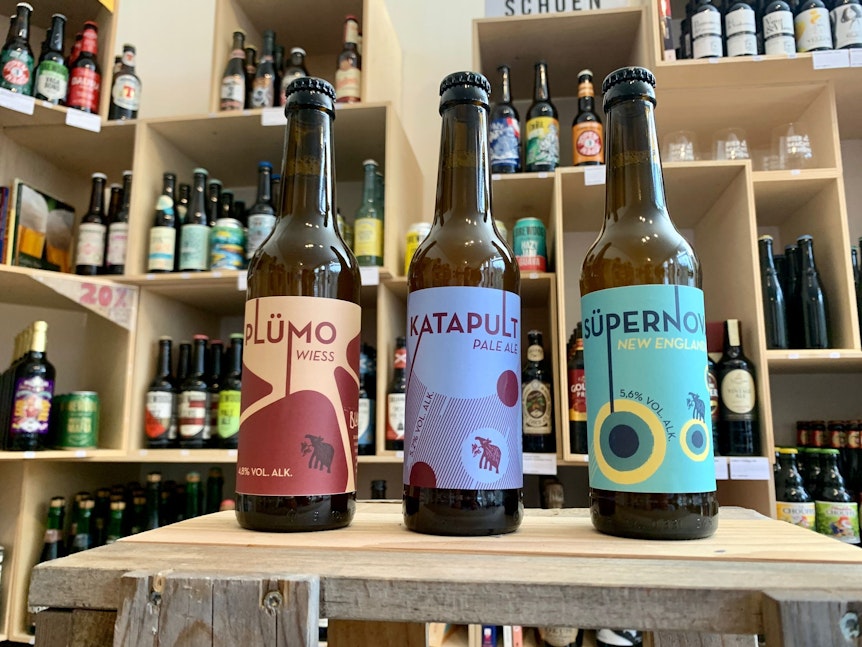 Drei Bierflaschen von Plümo, Katapult und Süpernova stehen auf einem Tisch.