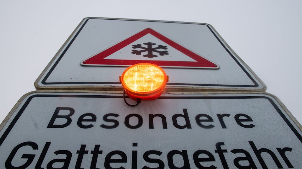 Ein Straßenschild warnt mit einer Blinkleuchte vor Glatteis.&nbsp;