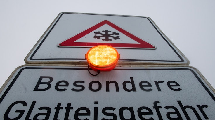 Ein Straßenschild warnt mit einer Blinkleuchte vor Glatteis