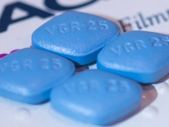 Vier Viagra-Tabletten liegen auf einer Viagra-Packung.