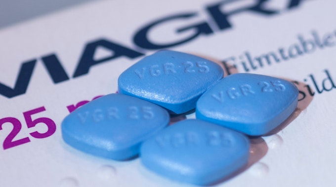 Vier Viagra-Tabletten liegen auf einer Viagra-Packung.