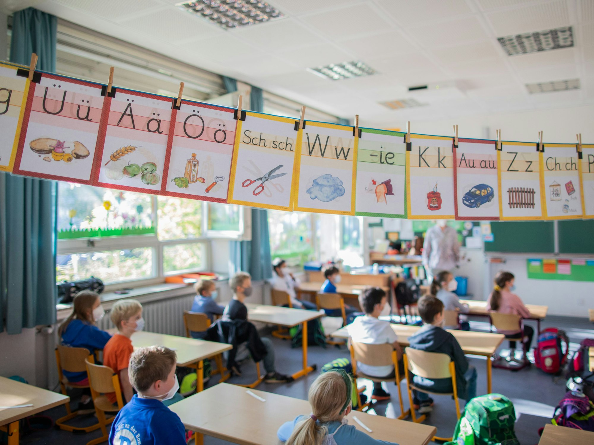 Schülerinnen und Schüler hören im Klassenzimmer ihrer Lehrerin zu. Foto von der dpa