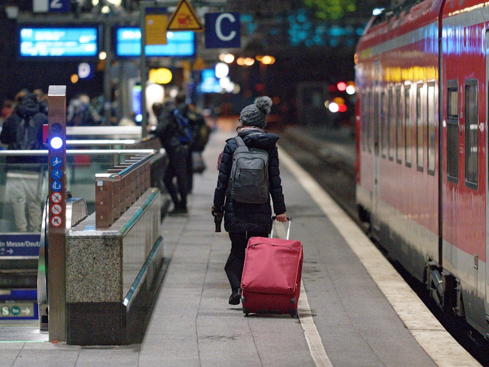 Eine Frau geht am Hauptbahnhof in Köln mit Koffer zu ihrem Zug. Foto von der dpa