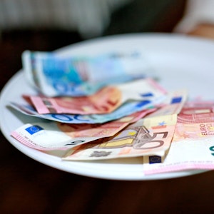 Undatiertes Foto von einer Kellnerin, die Geld auf dem Teller hat.