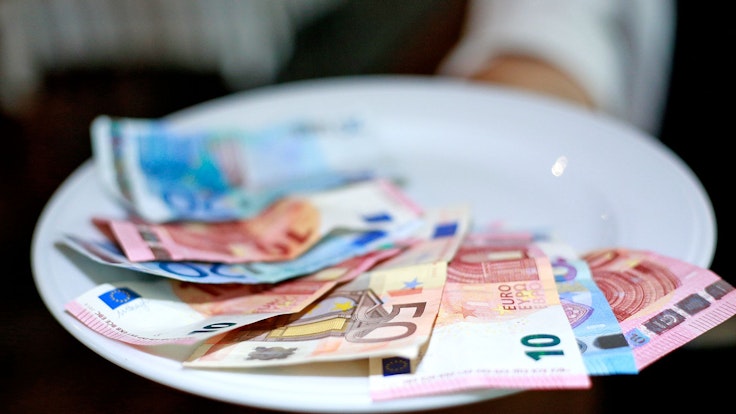 Undatiertes Foto von einer Kellnerin, die Geld auf dem Teller hat.