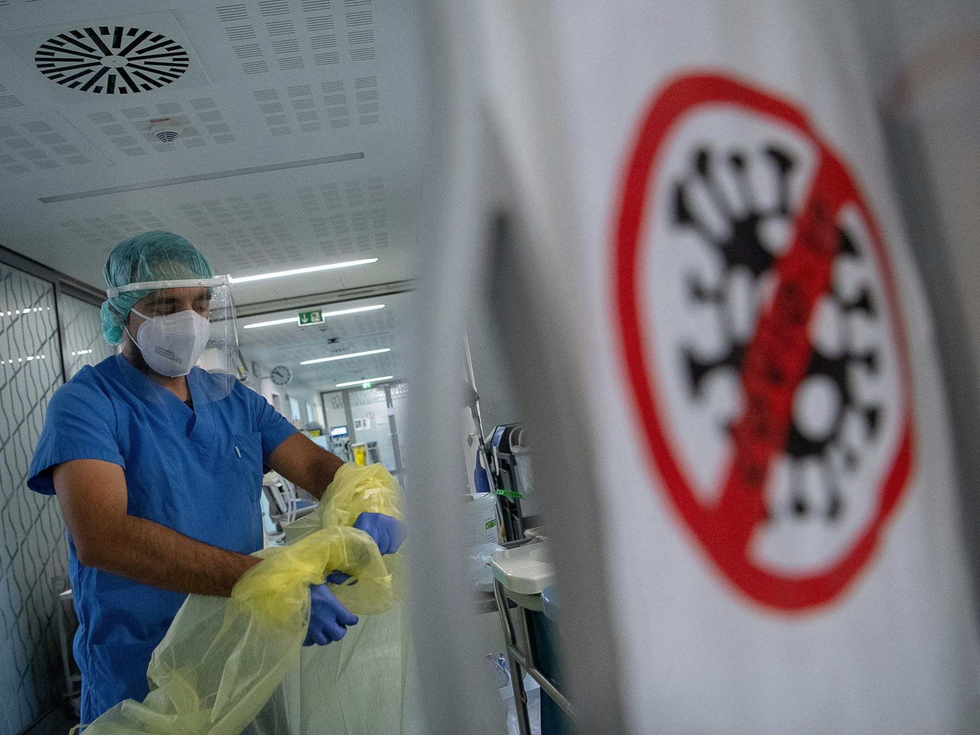 Ein Pfleger zieht beim Verlassen der Intensivstation für Corona-Patienten am Sana Klinikum Offenbach seinen Schutzkittel aus.