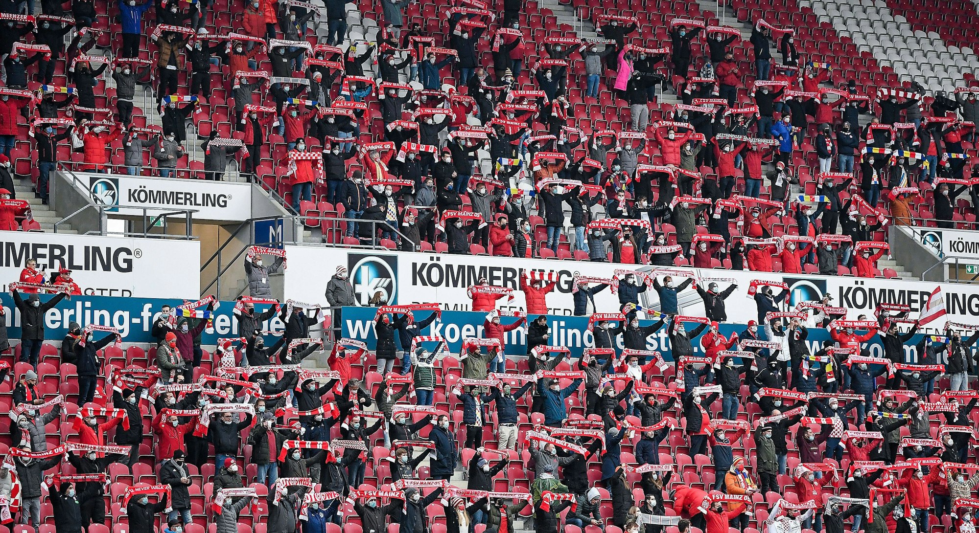 Fans des FSV Mainz 05 halten ihre Schals hoch. 