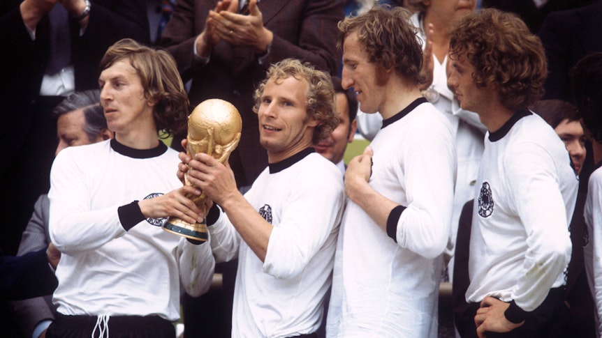 Gladbachs Rekordspieler Berti Vogts (2.v.l.) hält am 7. Juli 1974 im Münchner Olympiastadion nach dem Endspielsieg gegen die Niederlande stolz den Weltmeister-Pokal in seinen Händen. Rechts ist auch Gladbach-Legende Rainer Bonhof zu sehen.
