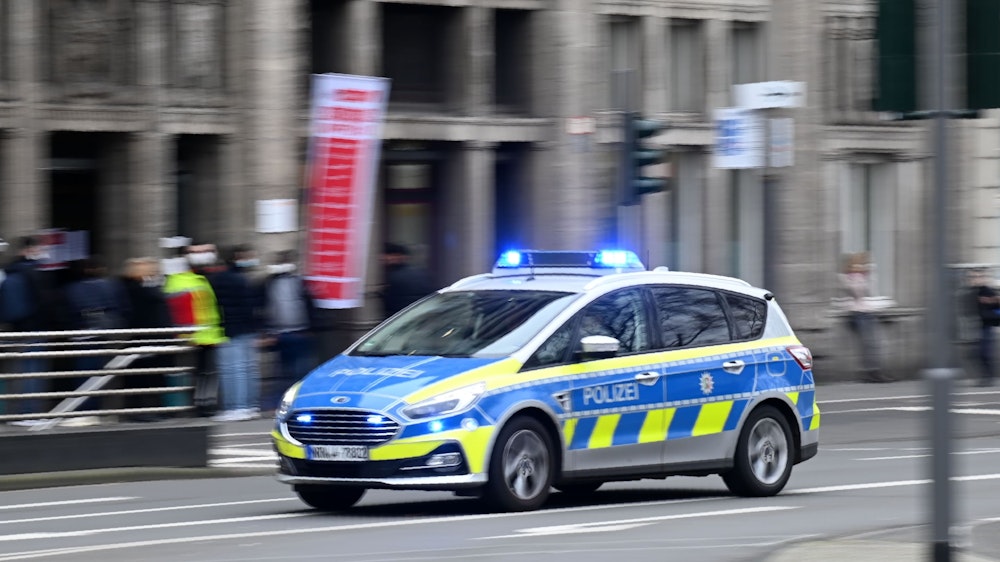 Ein Einsatzfahrzeug der Kölner Polizei fährt mit Blaulicht am Neumarkt vorbei.