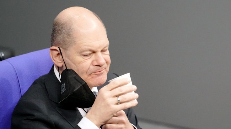 Bundeskanzler Olaf Scholz (SPD) nimmt an der Orientierungsdebatte zu einer SARS-CoV-2-Impfpflicht im Bundestag teil und trinkt etwas. Das Bild entstand am 26. Januar 2022.