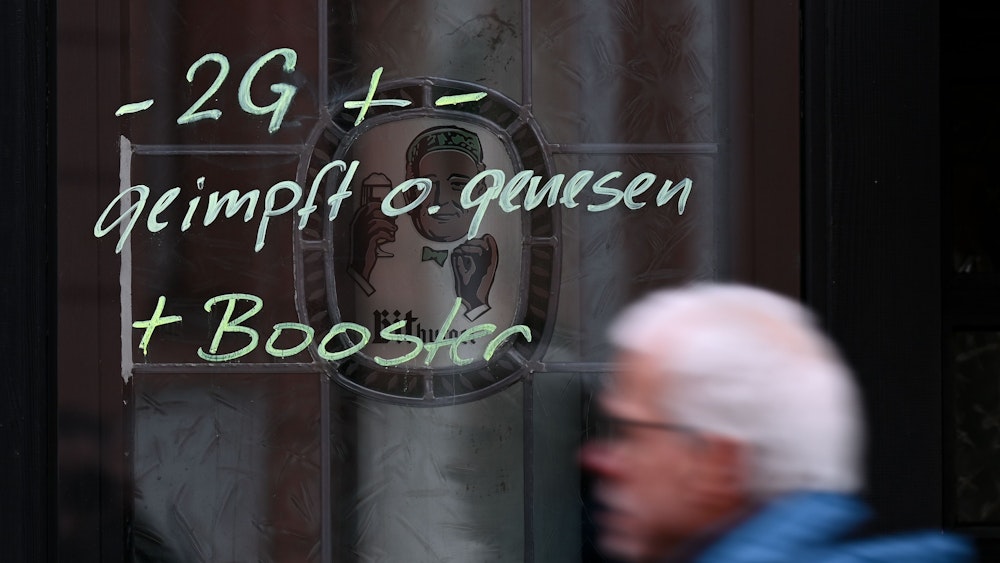 Am Fenster eines Lokals ist der Hinweis „-2G + - geimpft o. genesen + Booster“ aufgemalt.