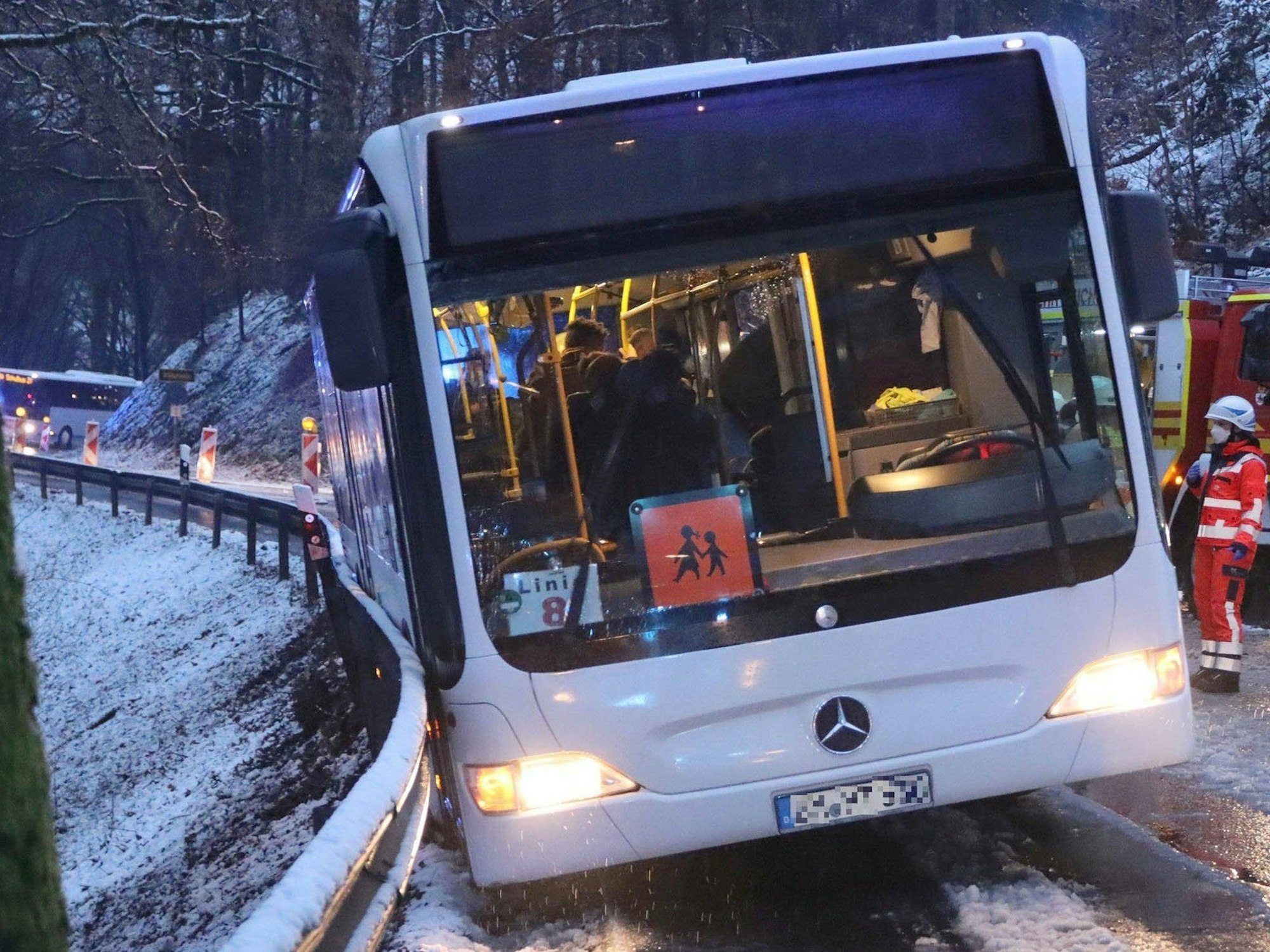 Ein Schulbus ist auf einer mit Schneematsch bedeckten Straße in die Leitplanke gerutscht.