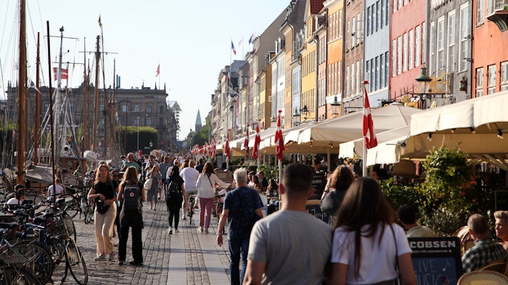 Passanten spazieren am Nyhavn entlang, dem bei Touristen beliebten Hafen mit seinen bunten Häuschen.