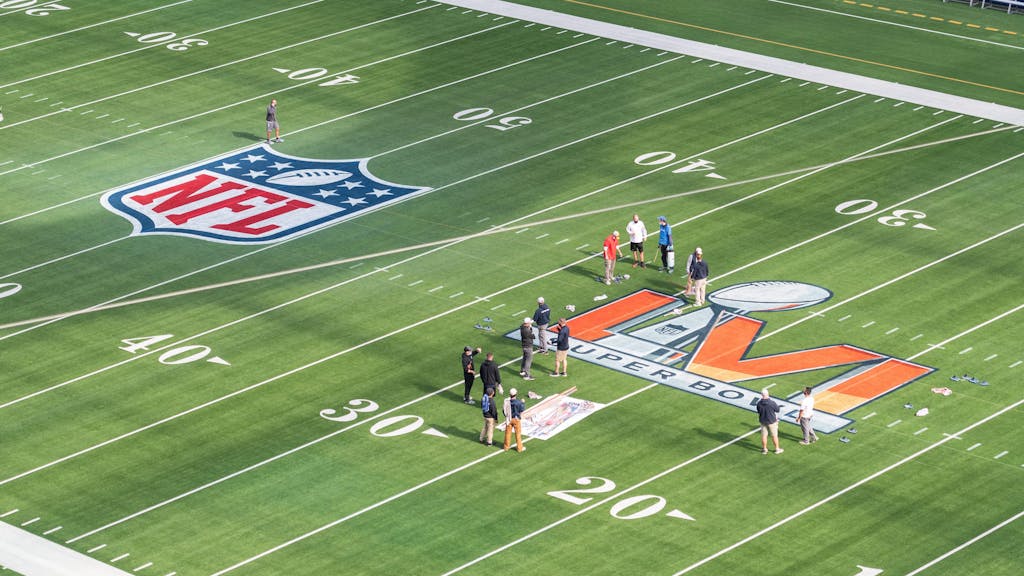 Arbeiter malen das Logo des Super Bowl LVI auf das Spielfeld im SoFi Stadium.