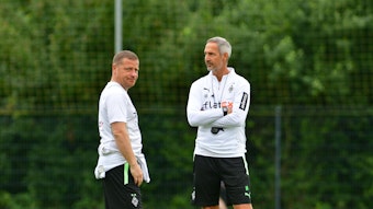 Adi Hütter (r.), Cheftrainer von Borussia Mönchengladbach, steht am 21. Juli 2021 gemeinsam mit dem ehemaligen Sportdirektor Max Eberl (l.) auf dem Trainingsplatz in Harsewinkel. Eberl schaut zum Fotografen herüber.