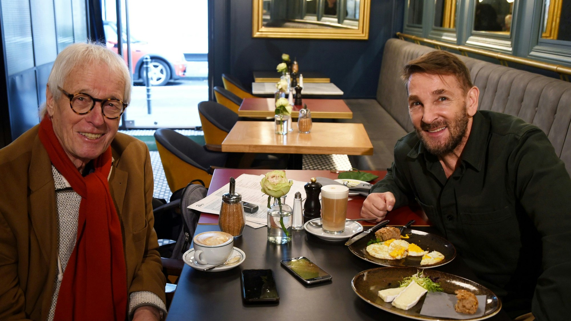 Horst Stellmacher (l.) und Mark Keller sitzen sich an einem Tisch gegenüber und lächeln in die Kamera.