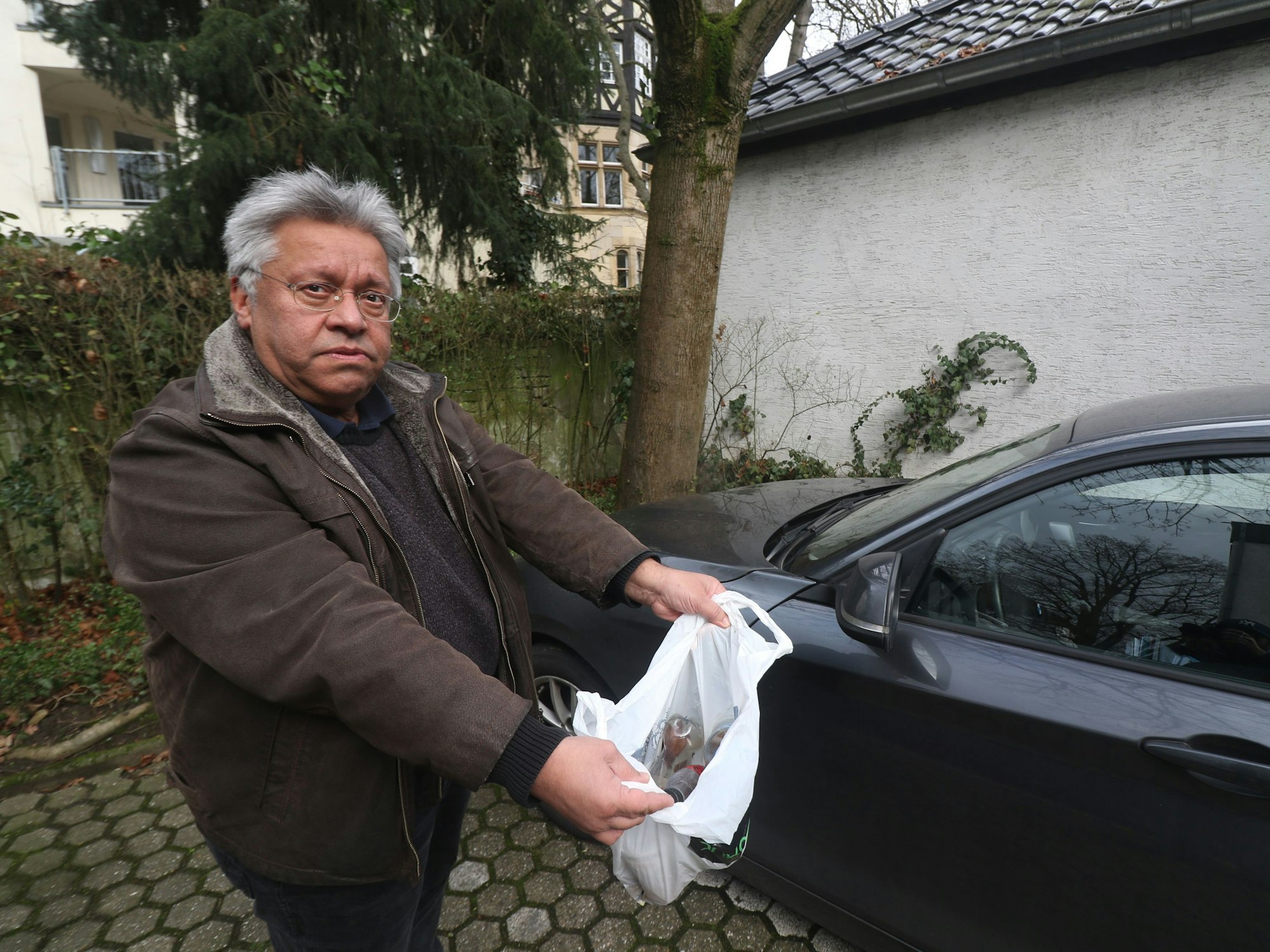 Der Kölner Mohammad Manavi hält eine Tüte voller Plastikflaschen mit Urin.