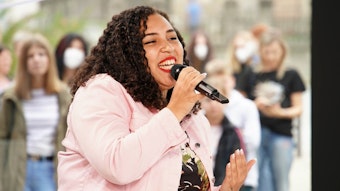 Das Foto zeigt die DSDS-Teilnehmerin Chantal Yancey, die mit einem Mikrofon vor dem Mund einen Song performt.