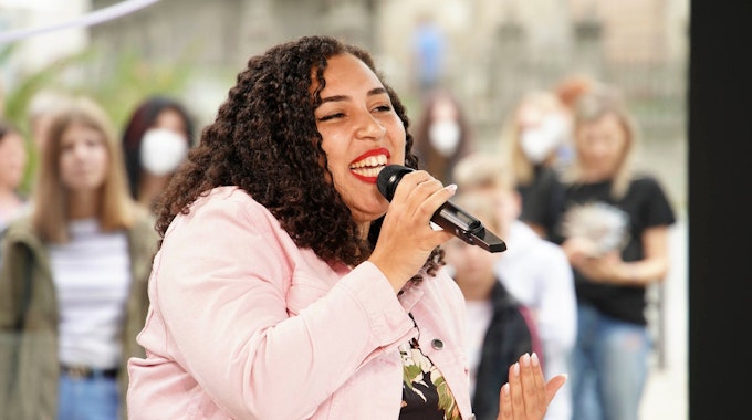 Das Foto zeigt die DSDS-Teilnehmerin Chantal Yancey, die mit einem Mikrofon vor dem Mund einen Song performt.
