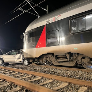 Ein Auto steht auf Gleisen vor einem Zug.