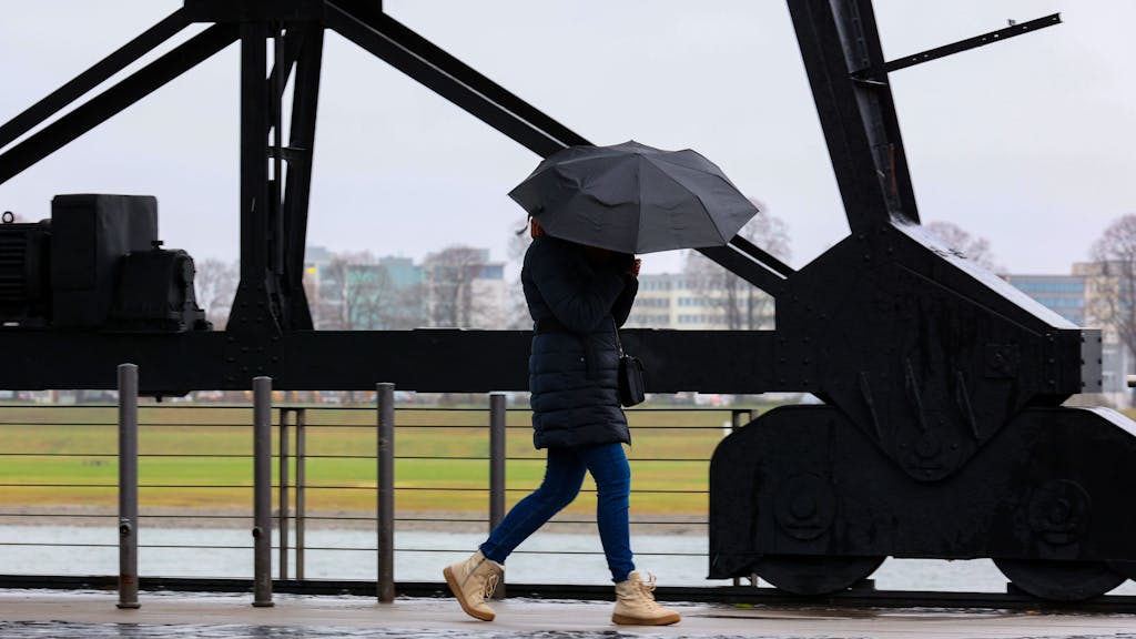 Köln:
Im Rheinauhafen versucht eine Fußgängerin Ihren Schirm fest zu halten.
Anhaltendes stürmisches Regenwetter über Köln.