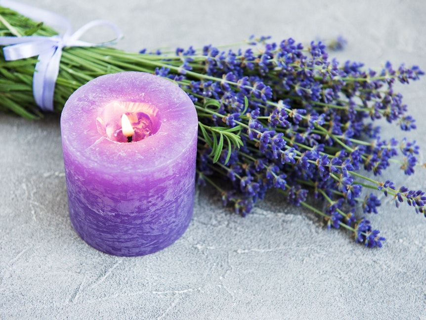 Eine Kerze aus Lavendelblüten duftet angenehm und entspannt.