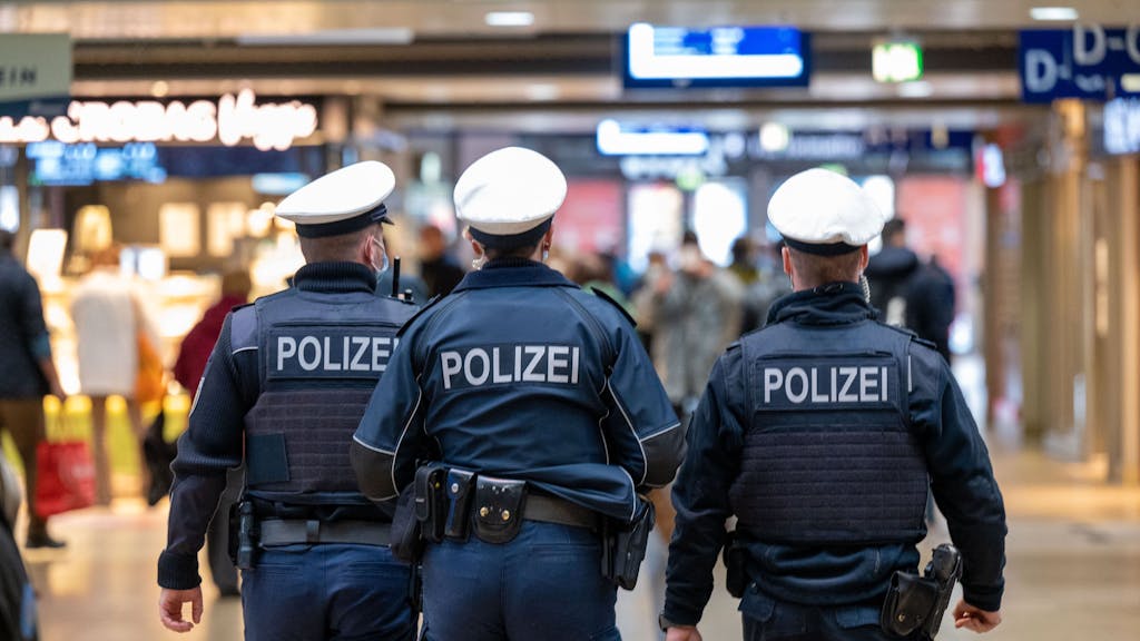 Drei Polizeibeamte laufen durch den Kölner Hauptbahnhof.
