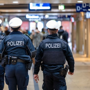 Drei Polizeibeamte laufen durch den Kölner Hauptbahnhof.
