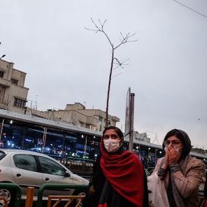 Iraner mit Schutzmasken gehen in unserem Archivbild vom Februar 2020 auf einer Straße in der Hauptstadt Teheran. Der Mord einer jungen Frau sorgt in dem Land derzeit für Entsetzen, Menschenrechtler fordern besseren Schutz für Frauen im Iran.