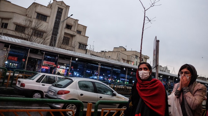 Iraner mit Schutzmasken gehen in unserem Archivbild vom Februar 2020 auf einer Straße in der Hauptstadt Teheran. Der Mord einer jungen Frau sorgt in dem Land derzeit für Entsetzen, Menschenrechtler fordern besseren Schutz für Frauen im Iran.