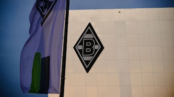 Der Borussia-Park in Mönchengladbach. Auf dem Neubau 8 Grad ist die Borussia-Raute zu sehen. Das Foto stammt vom 24. November 2020. Im Vordergrund ist eine Fahne.