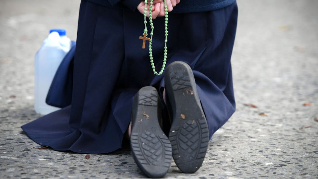 In den USA wurde eine 80-jährige Nonne zu einer Gefängnisstrafe verurteilt. Das Symbolfoto vom 1. November 2021 zeigt eine Nonne, die während einer Messe in der Grotte von Massabielle in der Wallfahrtskirche der Muttergottes, kniet und einen Rosenkranz in den Händen hält.