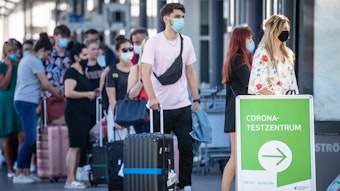 Reiserückkehrer stehen mit Mundschutz vor dem Corona-Testzentrum am Flughafen Stuttgart.
