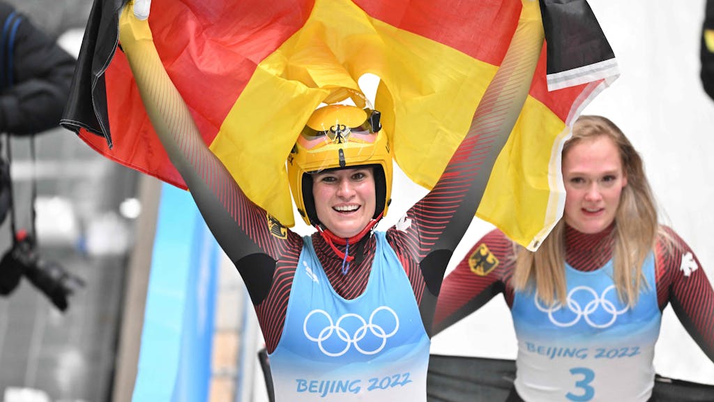 Natalie Geisenberger jubelt mit der deutschen Flagge.