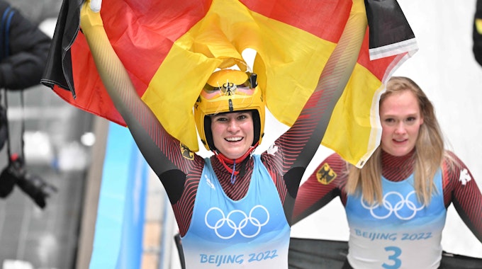Natalie Geisenberger jubelt mit der deutschen Flagge.