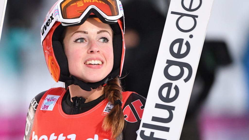 Skispringerin Juliane Seyfarth aus Deutschland lacht nach ihrem Sprung bei dem Weltcup.