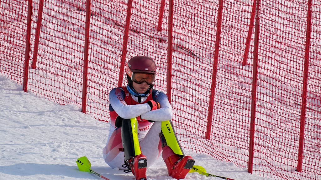 Mikaela Shiffrin sitzt nach ihrem Slalom-Aus frustriert im olympischen Schnee.