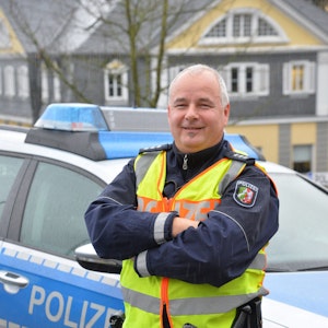 Polizist Rolf Stangenberg vor einem Polizei-Auto.