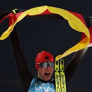 Vinzenz Geiger jubelt mit Deutschland-Fahne bei Olympia in China.