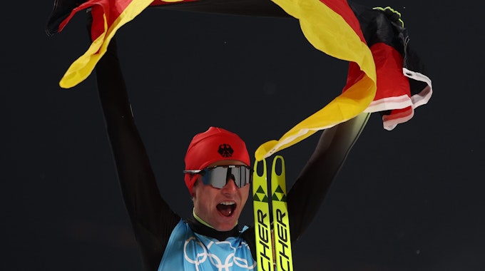 Vinzenz Geiger jubelt mit Deutschland-Fahne bei Olympia in China.