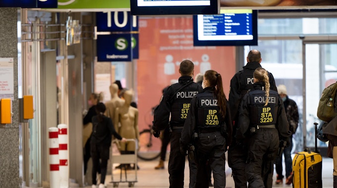 Bundespolizistinnen und -polizisten gehen in einer Gruppe durch einen Hauptbahnhof.